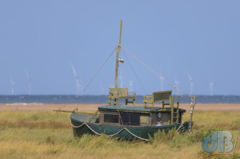 A boat on the marsh with offshore windturbines in the background - Landlocked windpower