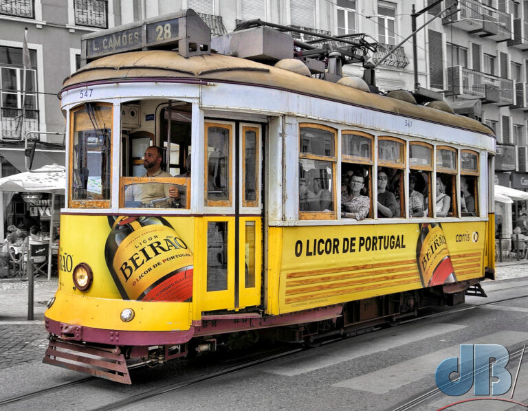 Old yellow Lisbon tram. Background and passengers desaturated